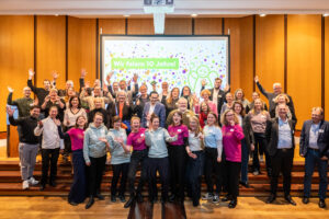 Ein Gruppenfoto mit ungefähr 50 Personen die die Hände hochhalten und lachen